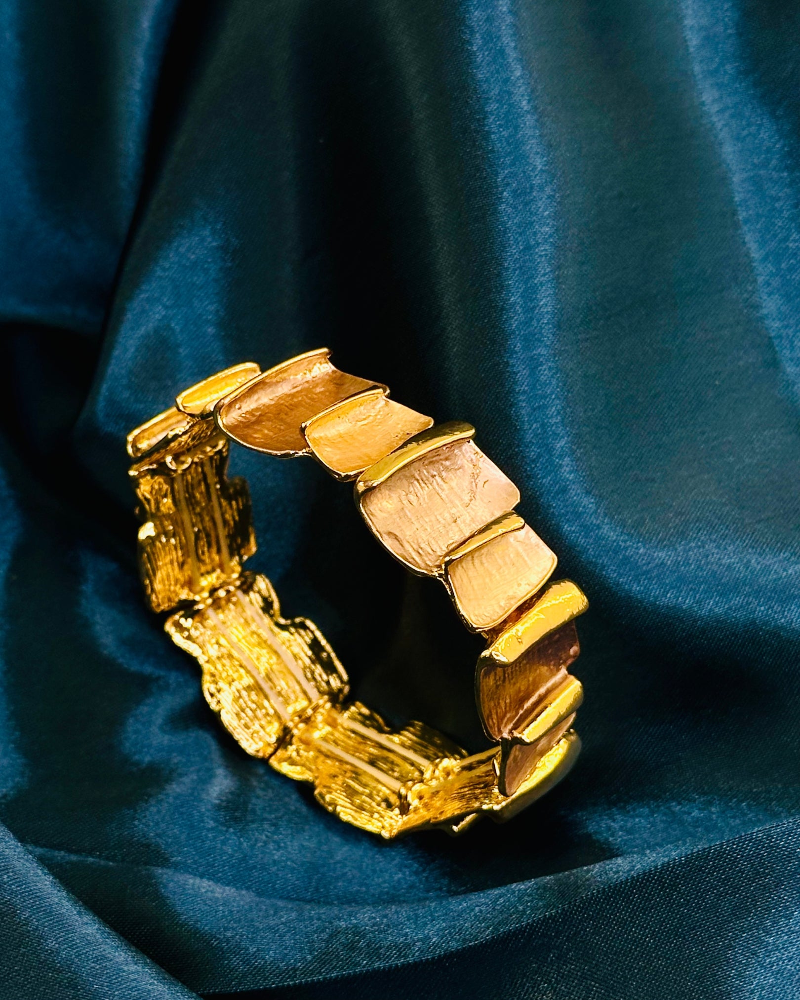 Gold bracelet on a blue fabric background